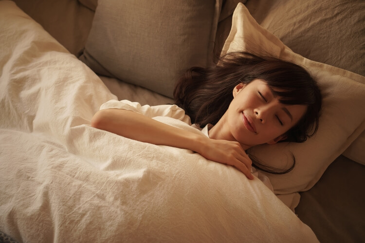 空気清浄機のかかった部屋で睡眠をとる女性