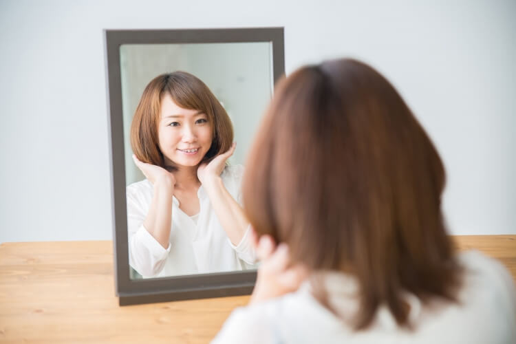 鏡で自分の髪を確認する女性