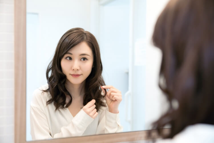 鏡の前で髪を触る女性