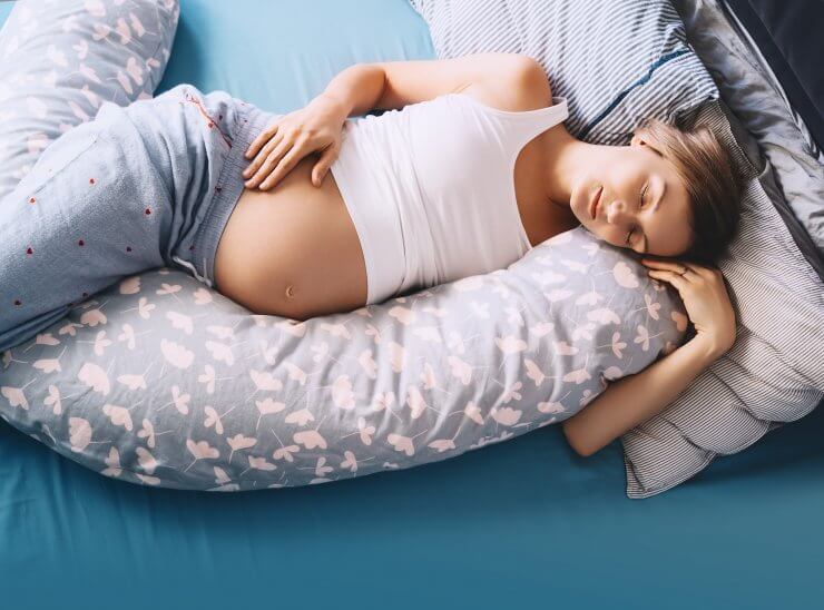 抱き枕を抱えて寝る妊婦