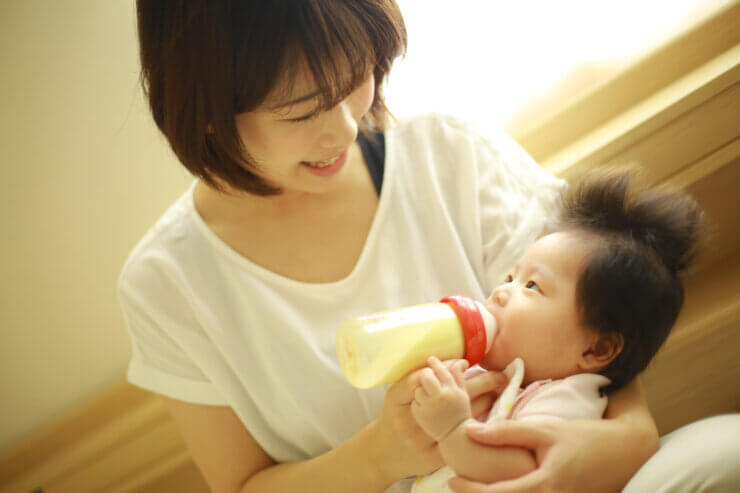 やわらかな灯りのもとで赤ちゃんにミルクをあげるママ
