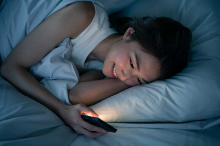 ベッドの中で寝る間際までスマホを見るのも、睡眠の質を下げる原因の一つ