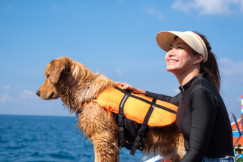 マリンレジャーを楽しむ女性とライフジャケットを着た愛犬