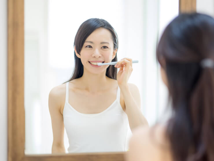 パウダー歯磨き粉を使った正しい磨き方、注意点。鏡を見ながら歯を磨いている女性